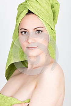 Beautiful Young woman dressed in a bath towel makes a cosmetic mask on the face. beauty industry and home skin care
