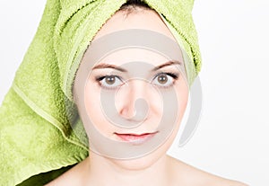 Beautiful Young woman dressed in a bath towel makes a cosmetic mask on the face. beauty industry and home skin care