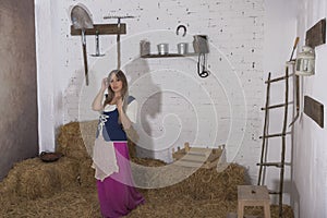 beautiful young woman, dressed in farmer outfit in barn with hay