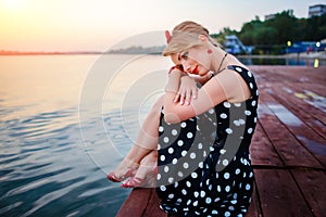 A beautiful young woman dressed sitting on the pier