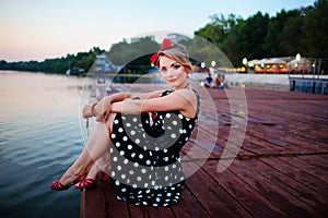 A beautiful young woman dressed sitting on the pier