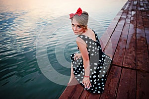 A beautiful young woman dressed sitting on the pier