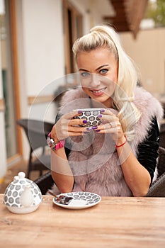 Beautiful young woman drink tea on bar terace in early autumn