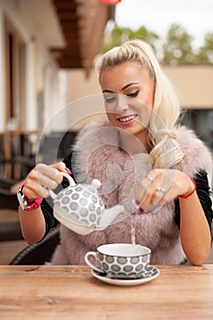 Beautiful young woman drink tea on bar terace in early autumn