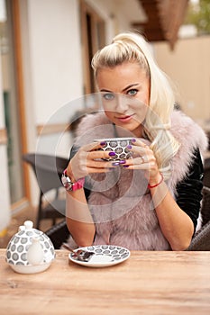 Beautiful young woman drink tea on bar terace in early autumn