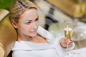 Beautiful young woman drinking champagne at spa