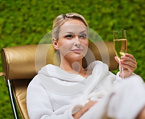 Beautiful young woman drinking champagne at spa
