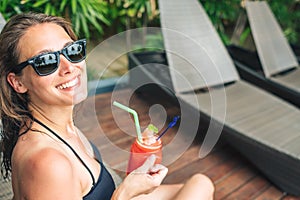 Beautiful young woman drinking cocktail while relaxing in sunbed