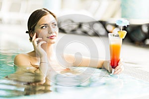 Beautiful young woman drinking a cocktail while in the swimming