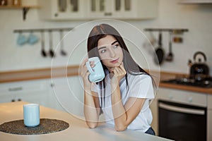 Beautiful young woman drinking a cup of coffee at home.