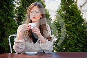 Beautiful young woman drinking hot coffee or tea in the morning at restaurant. Lifestyle photo, girl enjoying her morning coffee i