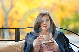 Beautiful young woman drinking hot tea outdoors