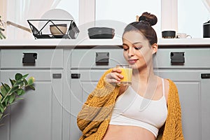 A beautiful young woman is drinking juice in her kitchen