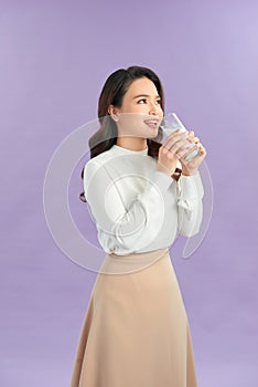 Beautiful young woman drinking milk on light background