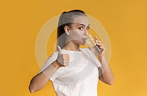 Beautiful Young Woman Drinking Mineral Water And Showing Thumb Up Gesture