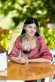 Beautiful young woman drinking red wine in cafe. Portrait with wine glass. Vocation holidays evening concept