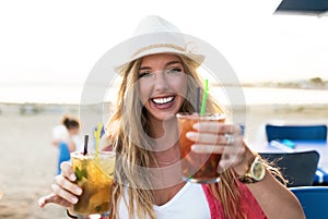 Beautiful young woman drinking refreshment on the beach.