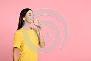 Beautiful young woman drinking tasty lemon water on background. Space for text