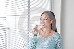 Beautiful young woman drinking water at home