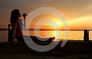 Beautiful young woman drinking water - sunset.