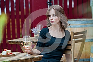 Beautiful young woman drinking white wine on the terrace of a restaurant.