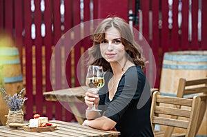 Beautiful young woman drinking white wine on the terrace of a restaurant. Relaxing after work with a glass of wine