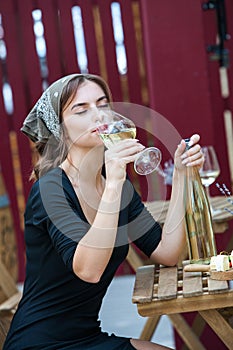 Beautiful young woman drinking white wine on the terrace of a restaurant. Relaxing after work with a glass of wine