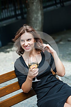 Beautiful young woman drinking white wine on the terrace of a restaurant. Relaxing after work with a glass of wine