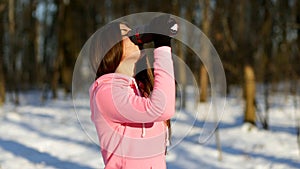 Beautiful young woman drinks tea after jogging in the winter forest.