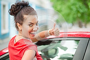 Beautiful young woman driver giving thumbs up showing car