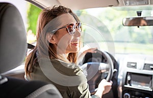 Beautiful young woman driving a car and wearing sunglasses