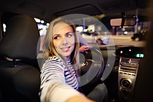 Beautiful young woman driving her car at night.