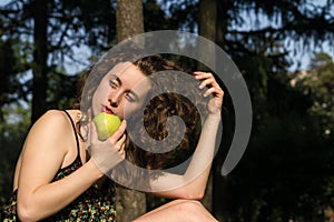 Beautiful young woman eating apple outdoors
