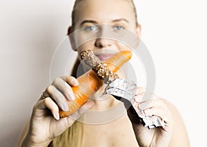 Beautiful young woman eating an carrot. carrot vs chocolate. healthy food - strong teeth concept