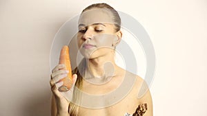 Beautiful young woman eating an carrot. carrot vs chocolate. healthy food - strong teeth concept