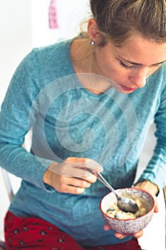 beautiful young woman eating cereals for breakfast in her Pajama