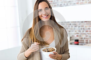 Beautiful young woman eating cereals at home.