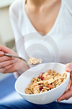Beautiful young woman eating cereals at home.
