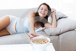Beautiful young woman eating cereals at home.