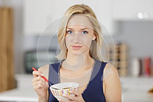 beautiful young woman eating cereals in kitchen for breakfast