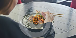 Beautiful young woman eating chinese food called Wok with chopsticks. Wok with meat and fried asparagus in a plate