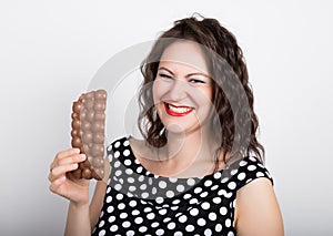 Beautiful young woman eating a chocolate bar, wears a dress with polka dots