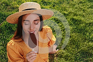 Beautiful young woman eating ice cream glazed in chocolate on green grass outdoors. Space for text