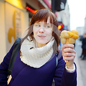 Beautiful young woman eating ice cream outdoors