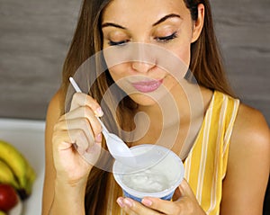 Beautiful young woman eating light Greek yogurt at home. Close up from above. Healthy concept