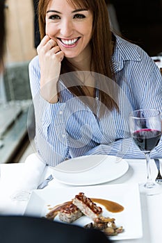 Beautiful young woman eating meatloaf in the restaurant.