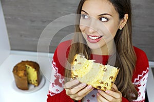 Beautiful young woman eating a slice of Panettone on Christmas holiday. Close up from above looking to the side. Copy space