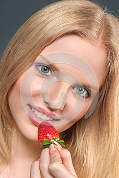 Beautiful young woman eating strawberry