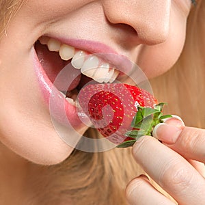 Beautiful young woman eating strawberry