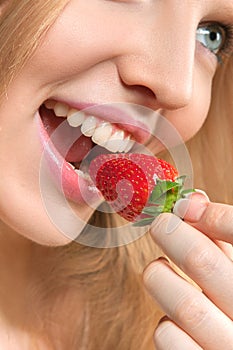 Beautiful young woman eating strawberry